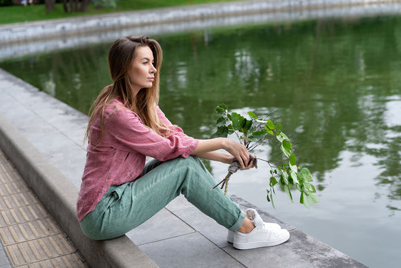 A young European girl Sitting curb on sidewalk near lake in city park